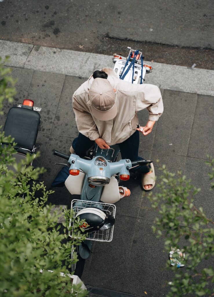 A man riding a moped down a street next to a forest